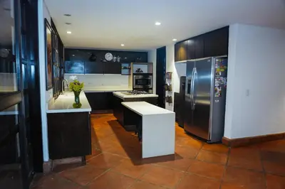 a kitchen with black cabinets and a stainless steel refrigerator at VILLA DOLLS PRIVADA CON SAUNA, PISCINA Y MAs in Rionegro
