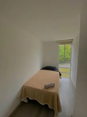 a bed in a white room with a window at Apartamento en Manizales in Manizales