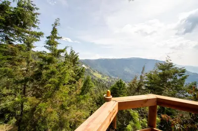 a wooden deck with a view of the mountains at Glamping, Jacuzzi, Malla Catamarán y Desayuno en Santa Elena in Medellín