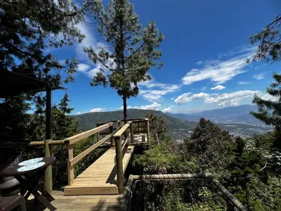 a wooden boardwalk with a view of the mountains at Glamping, Jacuzzi, Malla Catamarán y Desayuno en Santa Elena in Medellín