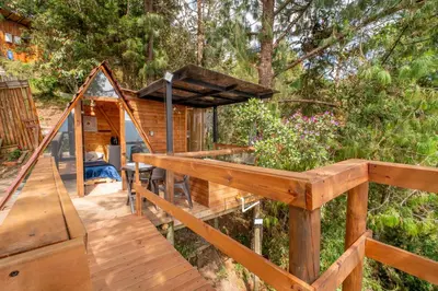 a wooden deck with a house in the woods at Glamping, Jacuzzi, Malla Catamarán y Desayuno en Santa Elena in Medellín