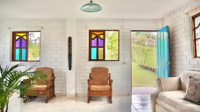 a living room with two chairs and stained glass windows at Casa Guatapé in Guatapé