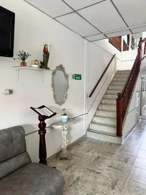a living room with a staircase with a chair and a mirror at Hotel Regional in La Dorada