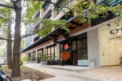 a building with a cafe on the side of the street at Kyux Studios by MOME in Medellín