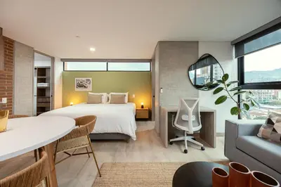 a bedroom with a bed and a table and a couch at Kyux Studios by MOME in Medellín