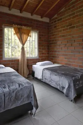 a bedroom with two beds and a brick wall at Finca campestre de 2 pisos en Guarne in Guarne