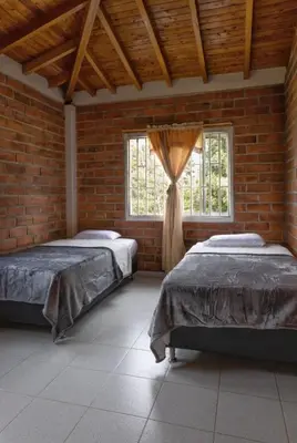 two beds in a room with a brick wall at Finca campestre de 2 pisos en Guarne in Guarne