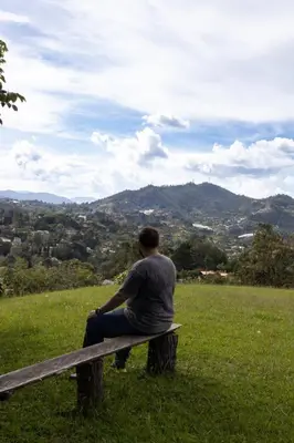 a man sitting on a bench in a field at Finca campestre de 2 pisos en Guarne in Guarne