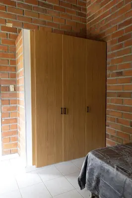 a bedroom with a brick wall and wooden cabinets at Finca campestre de 2 pisos en Guarne in Guarne