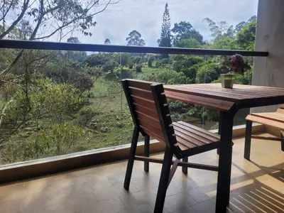 a wooden table and chair on a balcony with a view at Aparta Suite Hotel Rioverde Aeropuerto JMC in Rionegro