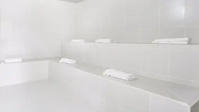 a white bathroom with white towels on a shelf at Aparta Suite Hotel Rioverde Aeropuerto JMC in Rionegro