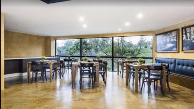 a restaurant with tables and chairs and large windows at Aparta Suite Hotel Rioverde Aeropuerto JMC in Rionegro