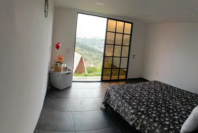 a bedroom with a bed and a large window at Stone's chalets Guatapé in Guatapé