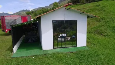 a small white dog house on a grassy hill at Stone's chalets Guatapé in Guatapé