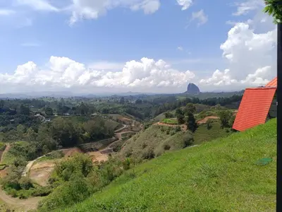 a view of a green hill with a red roof at Stone's chalets Guatapé in Guatapé