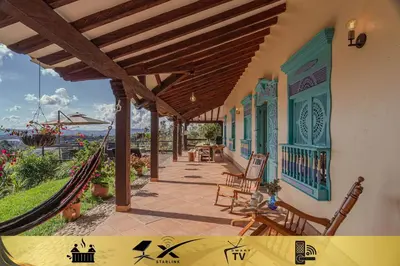 a porch of a house with chairs and a fence at Vista Bonita - Hacienda Guatape in Guatapé