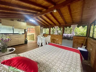 a bedroom with a large bed and a kitchen at Refugio del Pino santa elena in Santa Elena