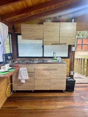 a kitchen with wooden cabinets and a sink at Refugio del Pino santa elena in Santa Elena
