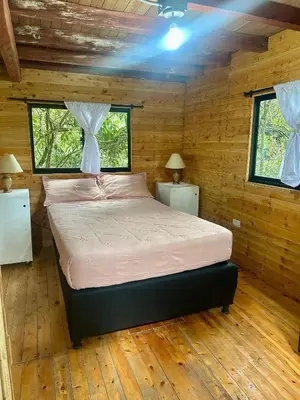 a bedroom with a bed in a wooden cabin at Refugio del Pino santa elena in Santa Elena