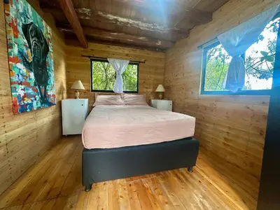 a bedroom with a bed in a wooden room at Refugio del Pino santa elena in Santa Elena