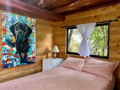 a bedroom with a black dog painting on the wall at Refugio del Pino santa elena in Santa Elena