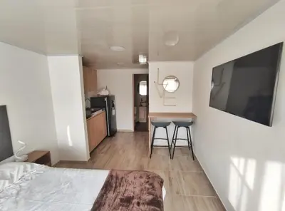 a bedroom with a bed and two stools and a kitchen at Apartaestudio S201 a 2 calles Milán Urbanevo in Manizales