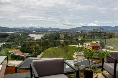 a balcony with chairs and a view of a city at Luxury Guatapé Loft with Starlink WiFi & Jacuzzi in Chiquinquirá