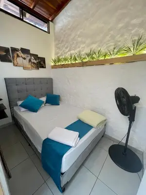 a bedroom with a bed with blue pillows and a fan at Apartamento cerca al aeropuerto Olaya herrera in Medellín