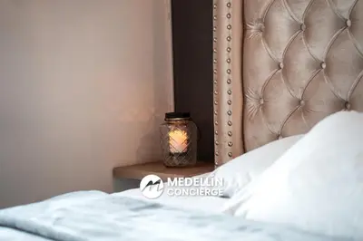a jar with a candle on a night stand next to a bed at 2BR House Jacuzzi & AC in Poblado Manila in Medellín