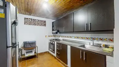 a kitchen with wooden cabinets and a sink and a refrigerator at Villa Armonía - Santa Fé de Antioquia in Santa Fe de Antioquia