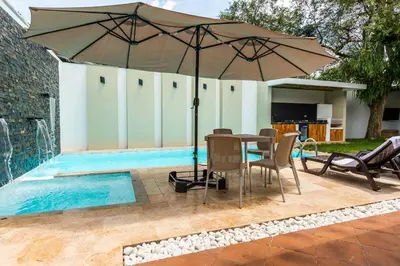 a table with an umbrella next to a swimming pool at Villa Armonía - Santa Fé de Antioquia in Santa Fe de Antioquia