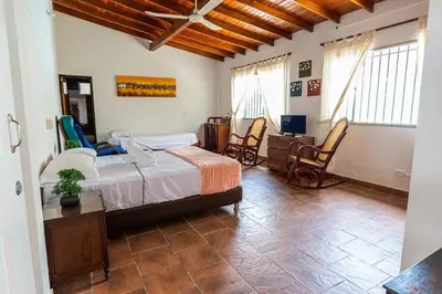 a bedroom with a bed and a desk and chairs at Villa Armonía - Santa Fé de Antioquia in Santa Fe de Antioquia
