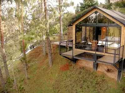 a cabin in the woods with a porch and a deck at Cabin - Jacuzzi - Frente al lago - Bosque in La Pradera