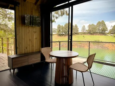 a table and chairs in a room with a large window at Cabin - Jacuzzi - Frente al lago - Bosque in La Pradera