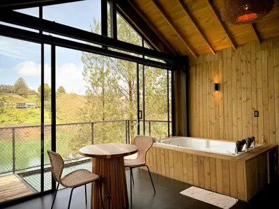 a room with a tub and a table and chairs at Cabin - Jacuzzi - Frente al lago - Bosque in La Pradera