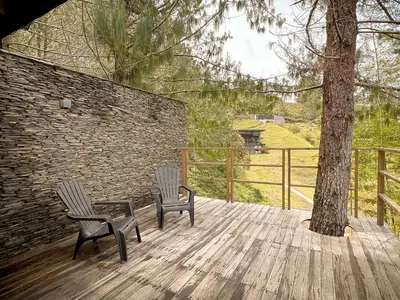 two chairs sitting on a wooden deck next to a tree at Cabin - Jacuzzi - Frente al lago - Bosque in La Pradera
