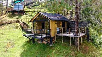 a tree house with two decks on the grass at Cabin - Jacuzzi - Frente al lago - Bosque in La Pradera
