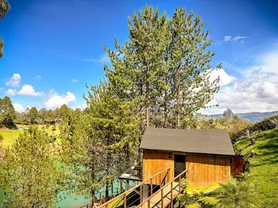 a wooden cabin with a bridge next to a lake at Cabin - Jacuzzi - Frente al lago - Bosque in La Pradera