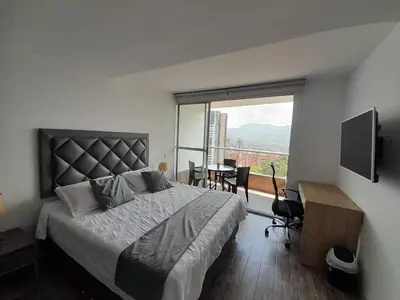 a bedroom with a bed and a desk and a window at Superior apto vista campestre in Sabaneta
