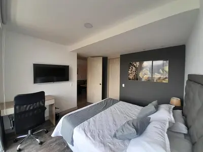 a bedroom with a bed and a desk and a television at Superior apto vista campestre in Sabaneta
