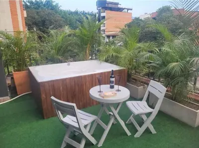 a table with a bottle of wine and two chairs on a patio at Amplio Apto con Jacuzzy Terraza 2B 4hab Laureles in Medellín