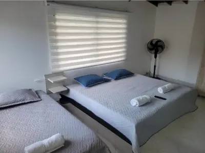 a bedroom with two beds with blue pillows and a window at Amplio Apto con Jacuzzy Terraza 2B 4hab Laureles in Medellín