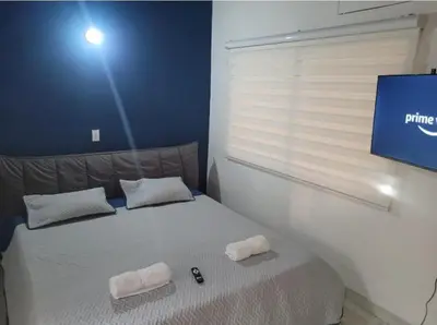 a bedroom with a bed with two pillows and a tv at Amplio Apto con Jacuzzy Terraza 2B 4hab Laureles in Medellín