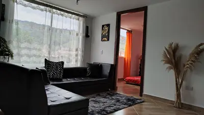 a living room with a black couch and a window at DESTINY Apto villas del Río in San Rafael