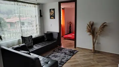 a living room with a black couch and a window at DESTINY Apto villas del Río in San Rafael