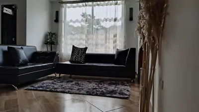 a living room with a black couch and a window at DESTINY Apto villas del Río in San Rafael