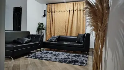 a living room with a black leather couch and a rug at DESTINY Apto villas del Río in San Rafael