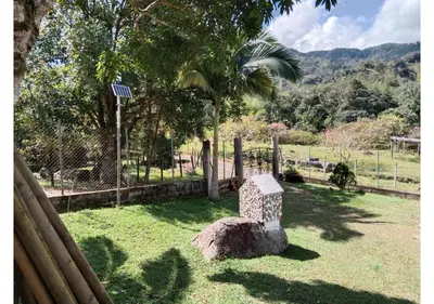 a stone bench sitting in the grass near a fence at Refugio en el arroyo in San Carlos
