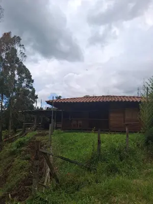 a building with a fence in front of a field at Cabaña los eucaliptos in Jardin