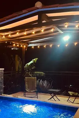 a patio with a swimming pool with lights and chairs at Villa Los Pinos in Sopetran